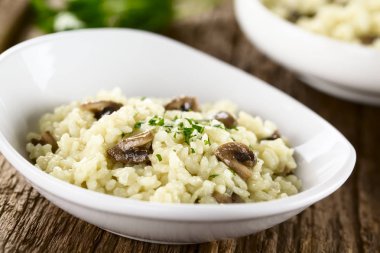 Beyaz kasede maydanozlu taze ev yapımı mantarlı risotto (Seçici Odak, ön taraftaki iki mantar parçasına odaklan)