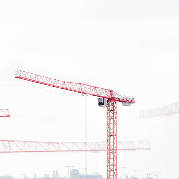Operating tower cranes against cityscape - construction and minimalism concept