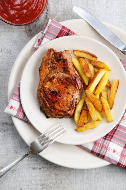 Sulu, usanmış domuz biftek kızarmış patates ile bir kemik üzerinde