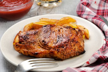 usanmış domuz biftek kızarmış patates ile bir kemik üzerinde.