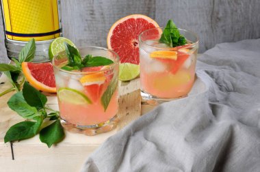 Kokteyl Londra Kuru Cin gelen suyu sıkılmış kırmızı greyfurt ve limon, limon dilimleri ve soğutulmuş buz küpleri hassas fesleğen yaprakları ile.