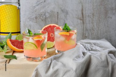 Kokteyl Londra Kuru Cin gelen suyu sıkılmış kırmızı greyfurt ve limon, limon dilimleri ve soğutulmuş buz küpleri hassas fesleğen yaprakları ile.