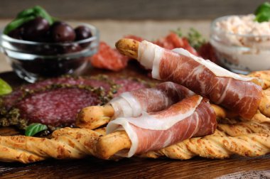  Salam, ekmek sopa (grisini) sarılmış meze aperatifler için çanak prosciutto ile zeytin ve peynir ahşap yüzeyde yapıştırın