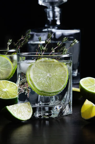 Cocktail with white rum and tonic, a slice of lime and thyme