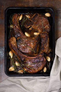 Sulu, bir dilim domuz pirzolası ve tavada sarımsak ve otla yağlı bir kemik. Düz Yatay