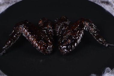 Yarasa kanatları. Tatlı ve ekşi sosta mürekkepbalığıyla pişirilmiş, tabakta ketçapla servis edilmiş. Cadılar Bayramı partisi için orijinal bir fikir.