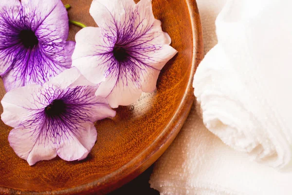 Twisted into roll white towels on a wooden Board closeup with purple flower.Flowers in wooden bowl and towel on wooden background
