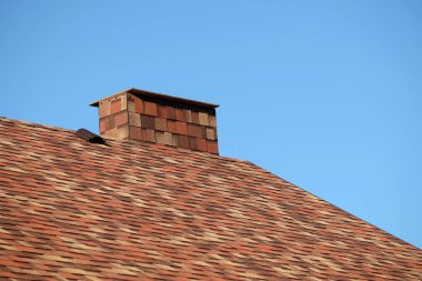 Kahverengi çatı rengarenk yumuşak Zona kısa büyük baca ile kaplı bir evin bir parçası kadar yakın bulutsuz mavi gökyüzü altında güneşli günde