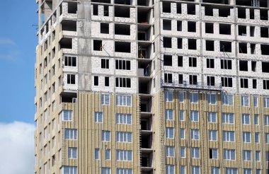 Üzerinde mavi gökyüzü bulutlar closeup ile bitmemiş modern kentsel ev apartman cephe yalıtımı montaj işlemi