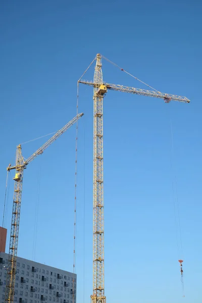 Big yellow construction tower crane on dwelling construction over blue sky