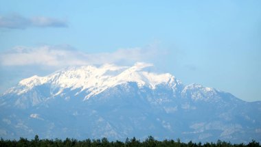 Bahar açık yeşil ormanda yukarıda üstleri beyaz kar kapaklar ile yüksek zaptedilemez Türk Dağları görüntülemek