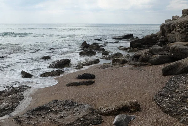 İle kıyı taşlarının üzerinde bulutlu hava çalıştıran dalgalar deniz manzara