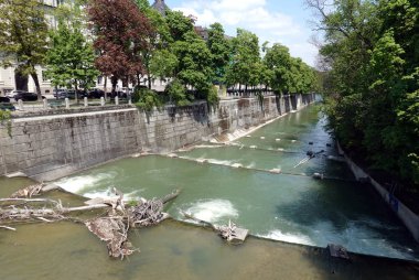 Hızlı nehir Isar güneşli bahar gününde Münih'te rapids sıkışmış ağaç gövdeleri bir sürü taş dolgu ile kenarlı