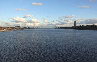 Demiryolu köprüsünden, Riga 'daki Daugava nehrine, oradan TV kulesine ve parlak güneşli bir günde kentsel mimariye sahip şehir manzarası.