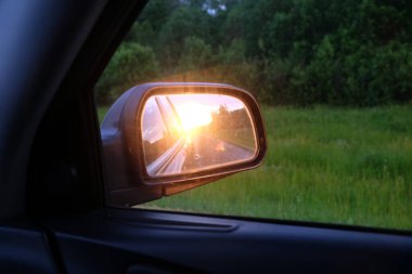 Araba camından yan aynaya, gün batımına akşam saatlerinde banliyö otobanında güneş ışığına bak.
