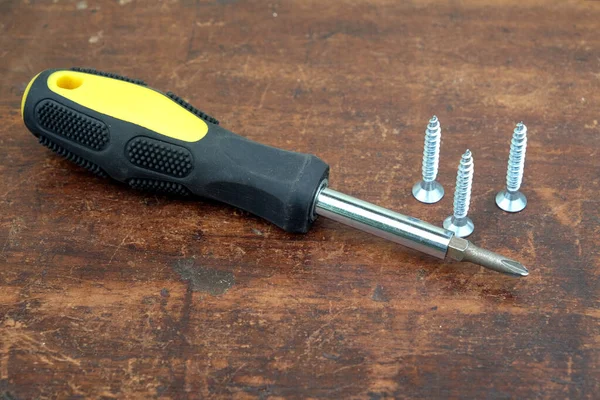 Handy Screw Driver Three Sharp Screws Brown Wooden Background Closeup — Stock Photo, Image