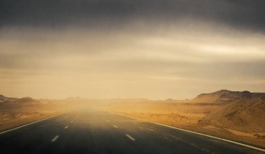 Panoramik bir bulutlu gökyüzü ve yol Çöl fırtınasında zamanda Afrika karayolu üzerinde. Doğrusal ve hava bakış açısı ile bulanıklık etkisi ve macera Posterinizi için metin için yer.