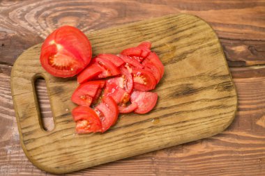 Bir bıçak ile doğrama tahtası üzerinde dilimlenmiş kırmızı domates.
