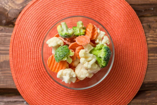 Taze dondurulmuş dilimlenmiş sebze - lahana, turuncu bir arka plan üzerinde bir tabakta havuç.