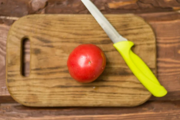 Fresh red tomato on a cutting wooden board with a knife. — Stock Photo, Image