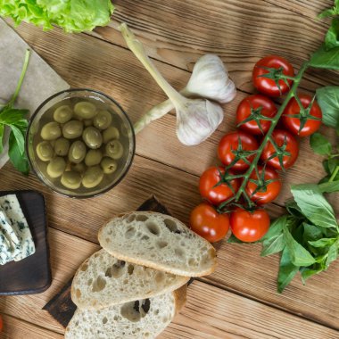 Bruschetta pişirme için Malzemeler: doğranmış ciabatta, zeytin, domates, ahşap bir arka plan üzerinde mavi peynir. Sağlıklı ve lezzetli yemekler pişirme.