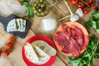 Bruschetta pişirme için Malzemeler: doğranmış ciabatta, zeytin, domates, mavi peynir, ahşap bir arka plan üzerinde jamon. Sağlıklı ve lezzetli yemekler pişirme.