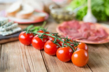 Ahşap bir arka plan üzerinde taze kiraz domates bir dalı.