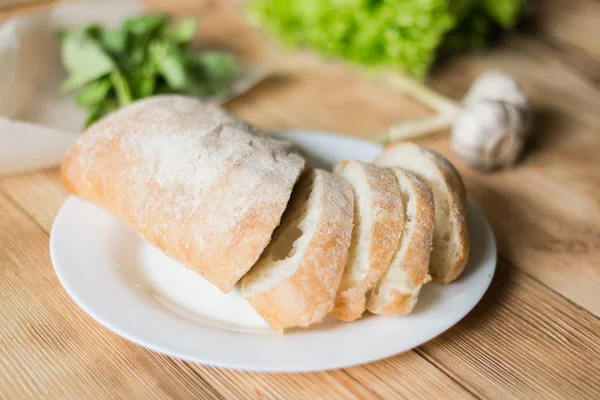 Pão fatiado, ciabatta num prato branco. Preparação para a preparação de bruschetta . — Fotografia de Stock