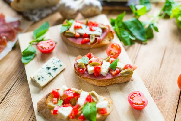 Cigatta tostada, un sándwich de queso con moho, tomates, albahaca sobre un fondo de madera . —  Fotos de Stock