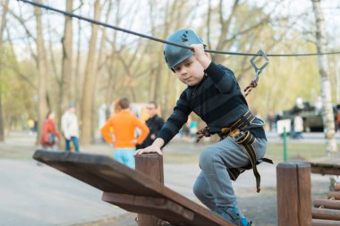 Küçük bir çocuk engelli parkurdan geçiyor. Parkta temiz havada çocuğun aktif fiziksel rekreasyon. Çocuklar için eğitim.