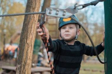 Küçük bir çocuk engelli parkurdan geçiyor. Parkta temiz havada çocuğun aktif fiziksel rekreasyon. Çocuklar için eğitim.