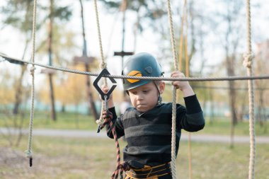Küçük bir çocuk engelli parkurdan geçiyor. Parkta temiz havada çocuğun aktif fiziksel rekreasyon. Çocuklar için eğitim.