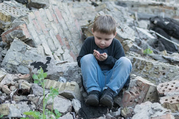 Kleiner Junge in der Nähe des zerstörten Hauses. Kinderkrankheiten, Einsamkeit. — Stockfoto