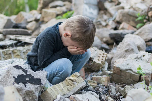 Un niño pequeño cerca de la casa destruida. Problemas infantiles, concepto de soledad . — Foto de Stock