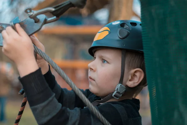 Een kleine jongen passeert een hindernisbaan. Actieve fysieke recreatie van het kind in de frisse lucht in het Park. Training voor kinderen. — Stockfoto