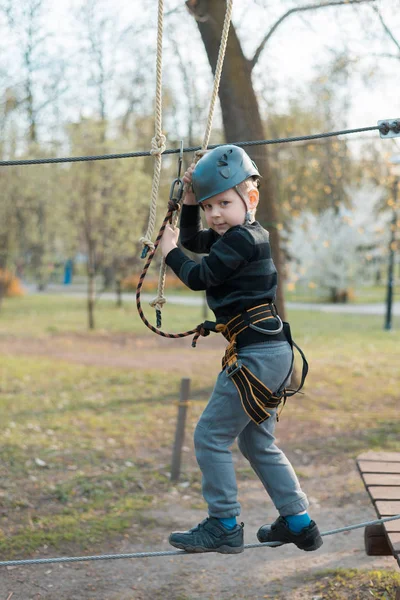 Um rapazinho está a passar um curso de obstáculos. Recreação física ativa da criança ao ar livre no parque. Treinamento para crianças . — Fotografia de Stock