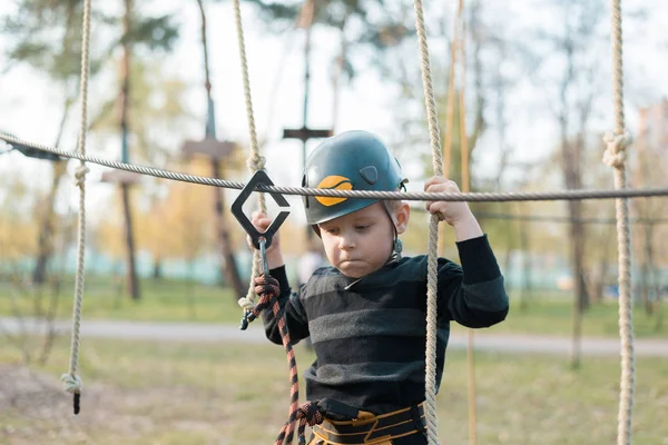 Küçük bir çocuk engelli parkurdan geçiyor. Parkta temiz havada çocuğun aktif fiziksel rekreasyon. Çocuklar için eğitim.
