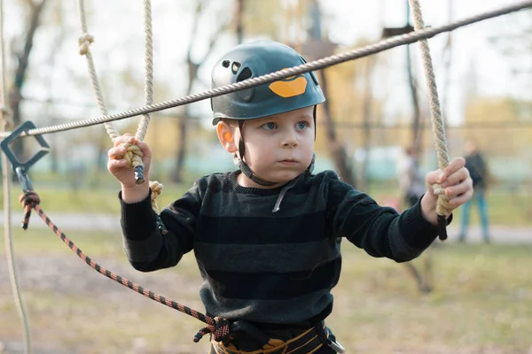 Küçük bir çocuk engelli parkurdan geçiyor. Parkta temiz havada çocuğun aktif fiziksel rekreasyon. Çocuklar için eğitim.