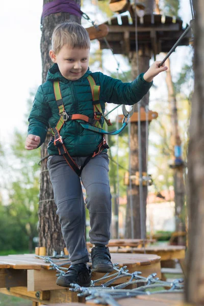 Kleine jongen in een touwenpark. Actieve fysieke recreatie van het kind in de frisse lucht in het park. Opleiding voor kinderen. — Stockfoto