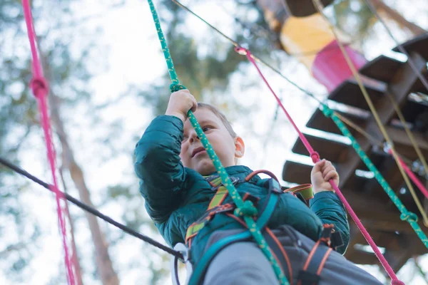 Kleine jongen in een touwenpark. Actieve fysieke recreatie van het kind in de frisse lucht in het park. Opleiding voor kinderen. — Stockfoto