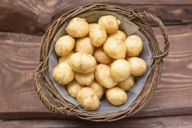 Ahşap bir arka plan üzerinde bir sepet içinde Çiğ taze organik patates.