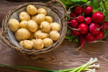 Taze çiğ organik sebzeler: patates, turp, ahşap bir arka plan üzerinde yeşil soğan.