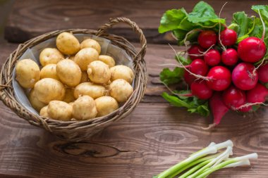 Taze çiğ organik sebzeler: patates, turp, ahşap bir arka plan üzerinde yeşil soğan.