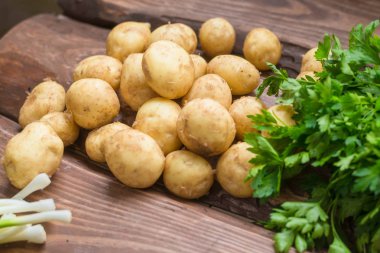 Taze çiğ organik sebzeler: patates, turp, ahşap bir arka plan üzerinde yeşil soğan.