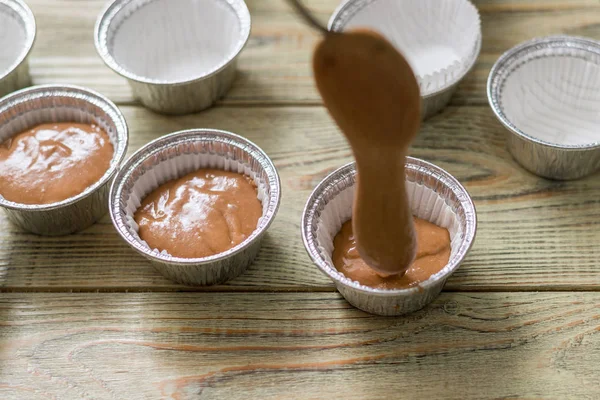 Massa de bolinho crua em assar pratos em fundo de madeira. Cozinhar muffins de chocolate . — Fotografia de Stock