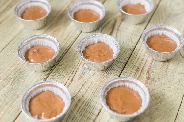 Massa de farinha crua para cozinhar em assadeira em fundo de madeira. Cozinhar muffins de chocolate . — Fotografia de Stock