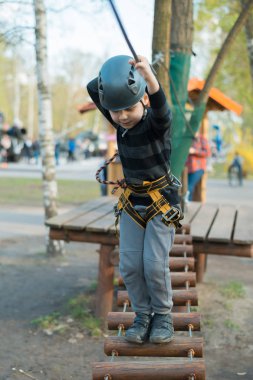 Küçük bir çocuk engelli parkurdan geçiyor. Parkta temiz havada çocuğun aktif fiziksel rekreasyon. Çocuklar için eğitim.