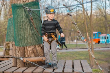 Küçük bir çocuk engelli parkurdan geçiyor. Parkta temiz havada çocuğun aktif fiziksel rekreasyon. Çocuklar için eğitim.