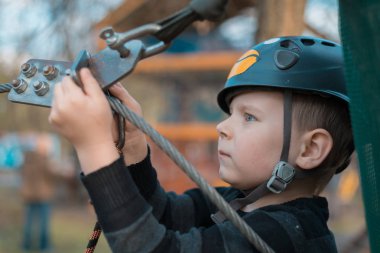 Küçük bir çocuk engelli parkurdan geçiyor. Parkta temiz havada çocuğun aktif fiziksel rekreasyon. Çocuklar için eğitim.