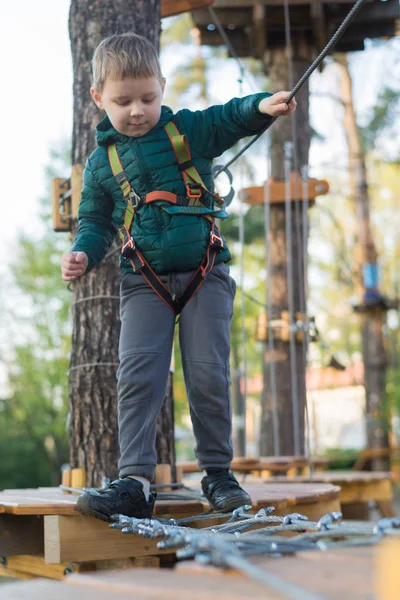 Kleine jongen in een touwenpark. Actieve fysieke recreatie van het kind in de frisse lucht in het park. Opleiding voor kinderen. — Stockfoto